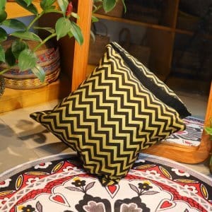 cotton cushion cover 16x16 inch with soft texture, placed on a wooden surface beside rattan furniture and green plants